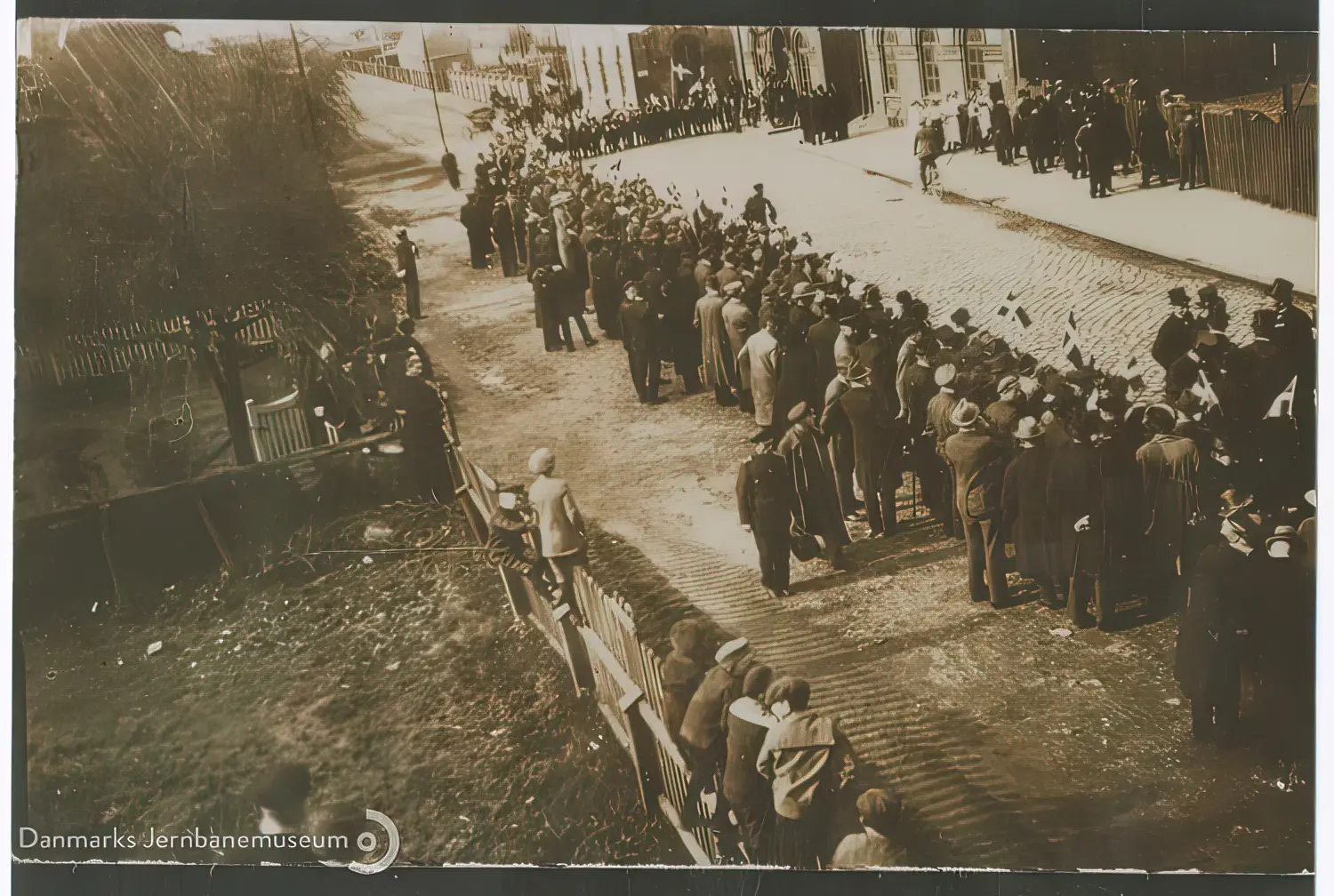 Billede af genforeningen - Tilskuere ved Sønderjysk Kommandos parade på Tønder H Stations forplads ved nuværende Jernbanegade. Mængden af tilskuere er lille - Tønder havde tysksindet befolkningsflertal. Billede af genforeningen - Tilskuere ved Sønderjysk Kommandos parade på Tønder H Stations forplads ved nuværende Jernbanegade. Mængden af tilskuere er lille - Tønder havde tysksindet befolkningsflertal.