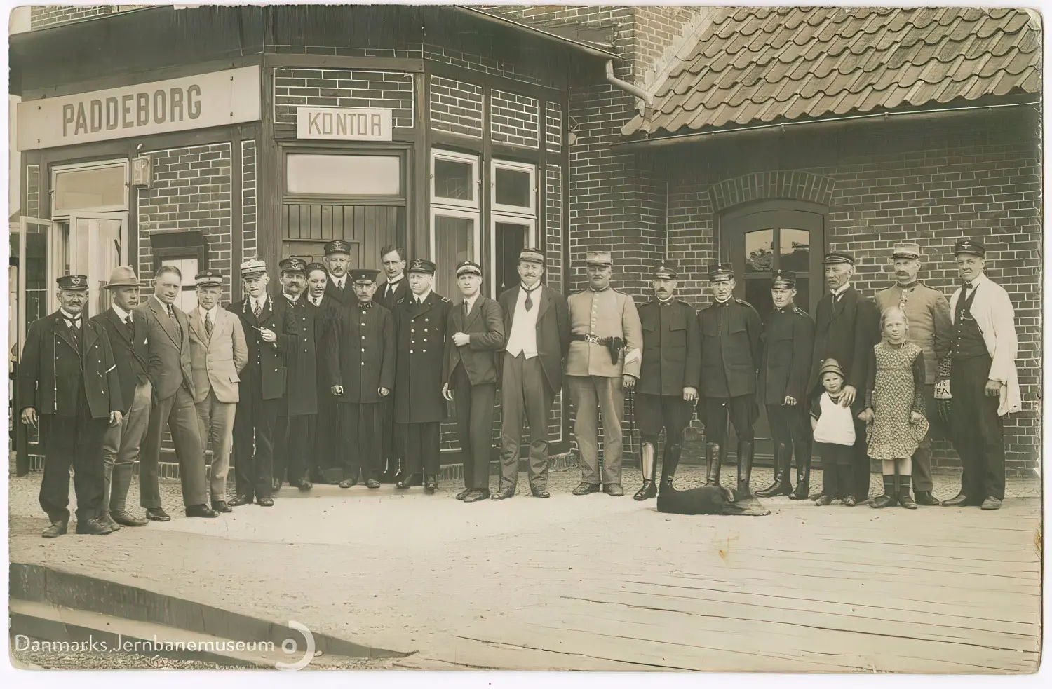 Billede af civile, toldere, politi, gendarmer og en enkelt tysk tjenestemand på perronen under det nye danske stationsnavneskilt efter den danske overtagelse af Padborg Station natten mellem den 16. og 17. jun. 1920. Billede af civile, toldere, politi, gendarmer og en enkelt tysk tjenestemand på perronen under det nye danske stationsnavneskilt efter den danske overtagelse af Padborg Station natten mellem den 16. og 17. jun. 1920.
